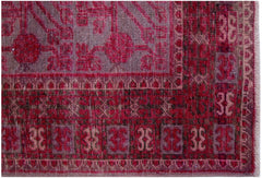 An antique handwoven Khotan rug featuring an intricate pomegranate pattern in shades of pink.
