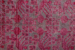 An antique handwoven Khotan rug featuring an intricate pink pomegranate pattern on a wool base.