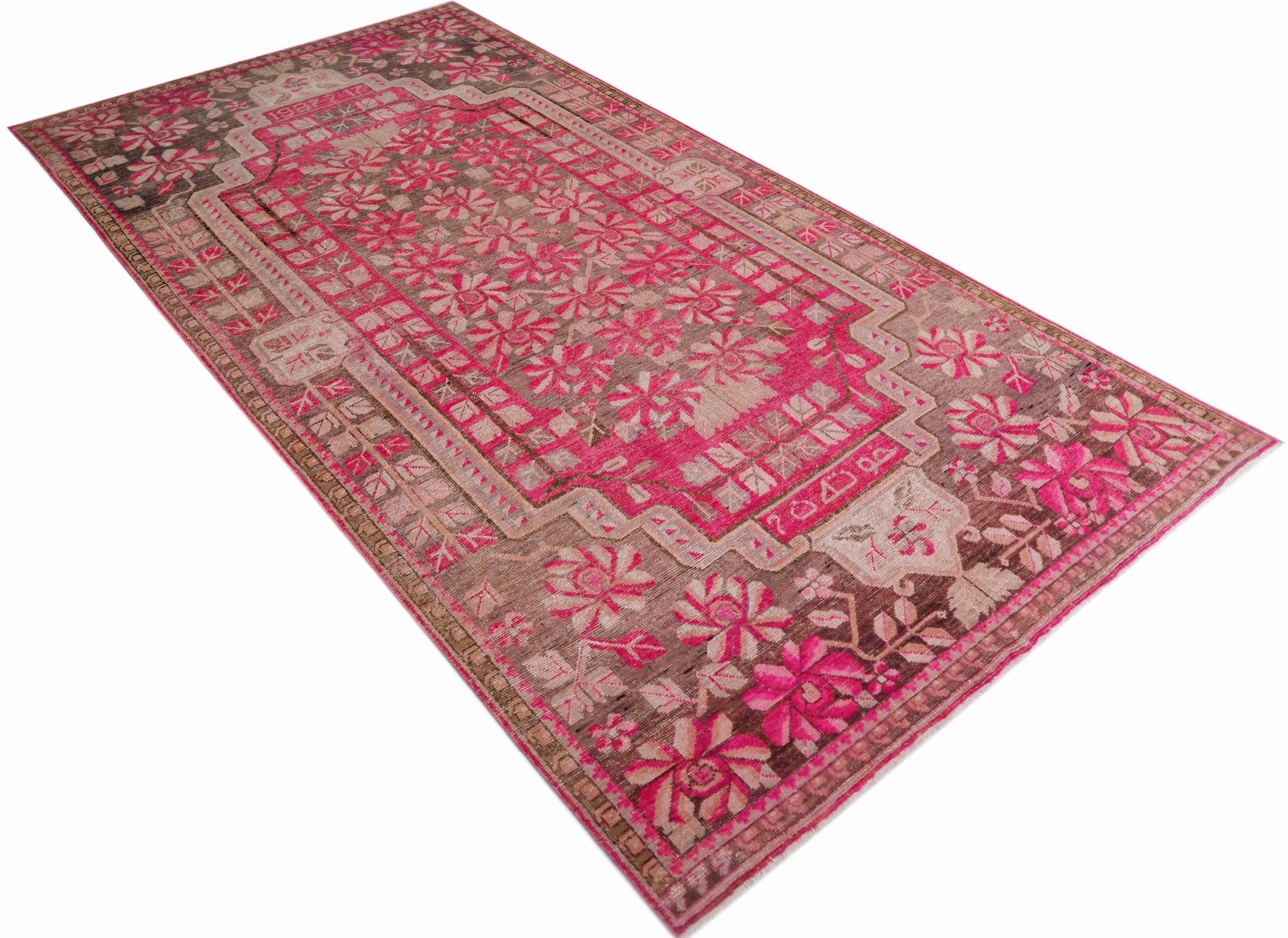 A vintage handwoven Khotan rug featuring a vibrant pink pomegranate pattern on a brown background.