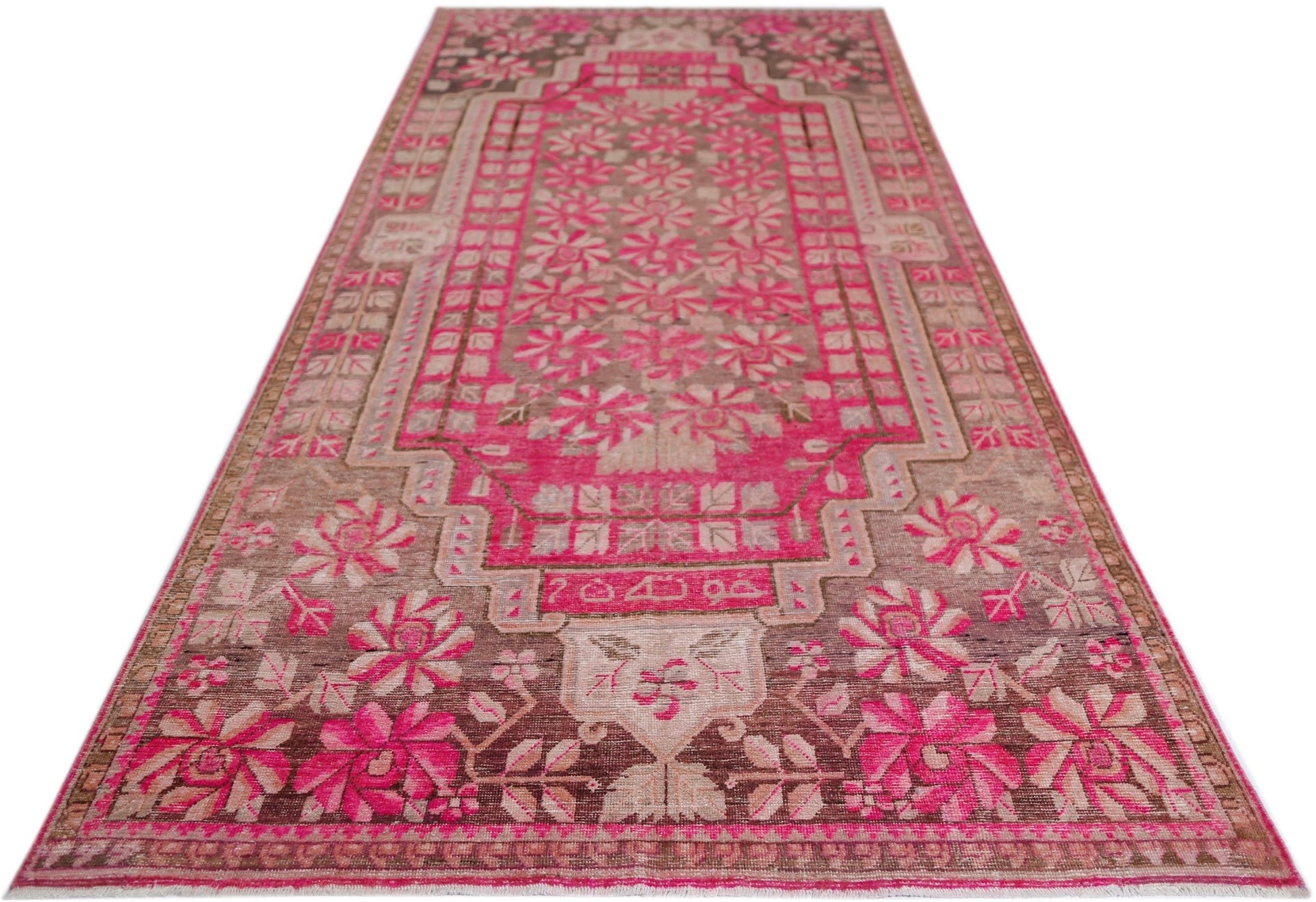 A vintage handwoven Khotan rug featuring an intricate pink pomegranate pattern on a brown base.