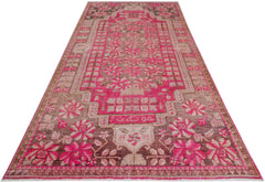 A vintage handwoven Khotan rug featuring an intricate pink pomegranate pattern on a brown base.
