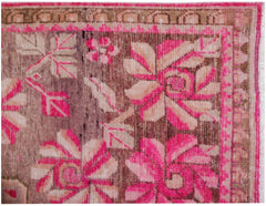 A vintage handwoven Khotan rug featuring a vibrant pink pomegranate floral pattern on a brown base.