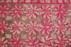 A vintage handwoven Khotan rug featuring an intricate pomegranate pattern in vibrant pink and brown.