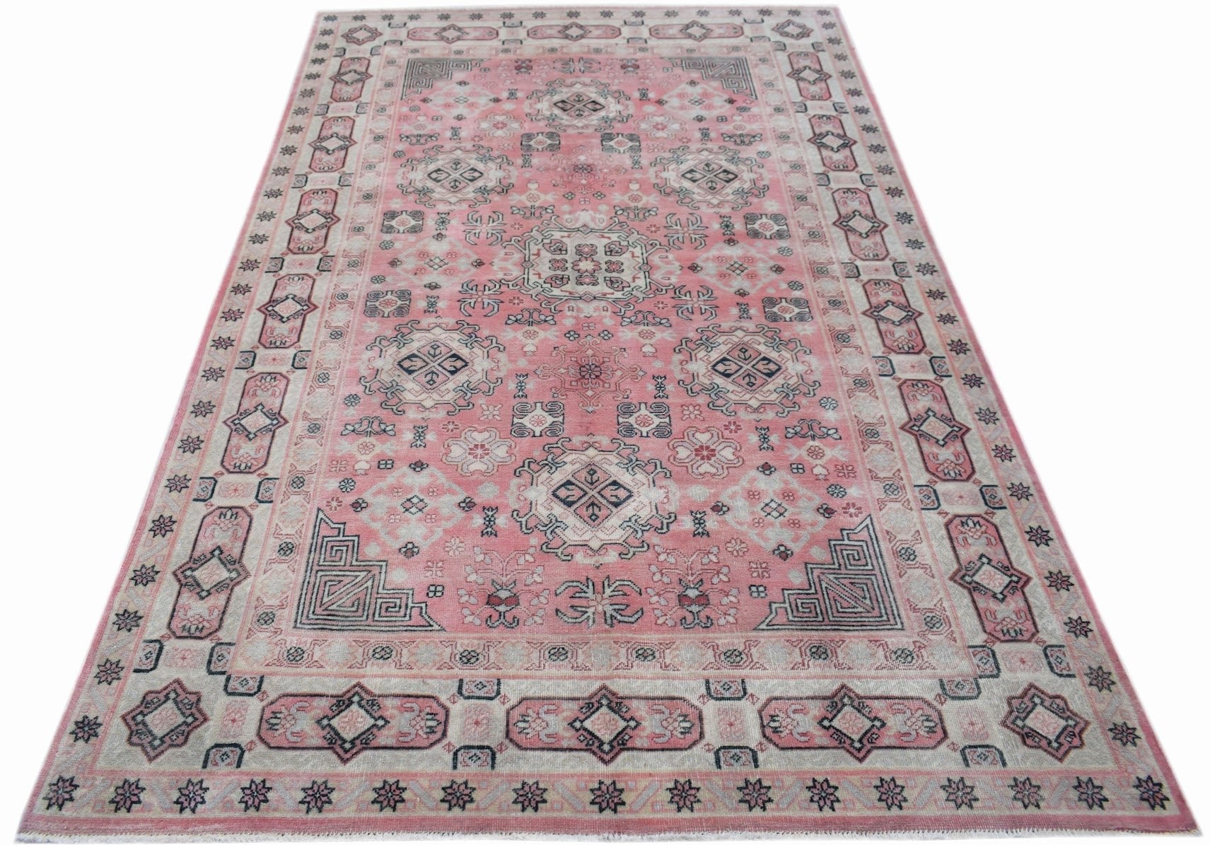 A vintage handwoven Chinese wool rug featuring a pink field with intricate geometric patterns.
