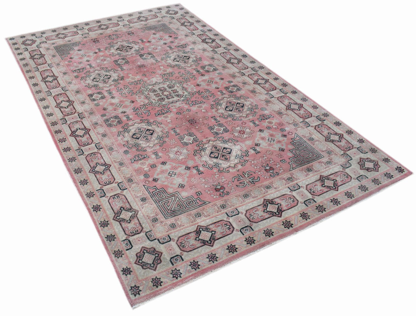 A vintage handwoven Chinese rug featuring a faded pink field with intricate geometric patterns.