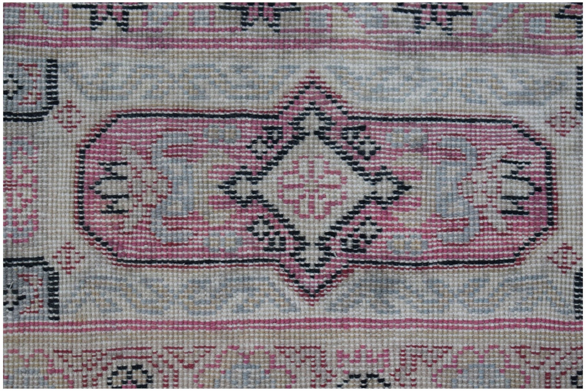 A vintage handwoven Chinese rug featuring a pink and grey geometric medallion pattern.