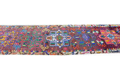 A vintage Kurdish Herki runner featuring vibrant geometric tribal motifs on a dark wool base.