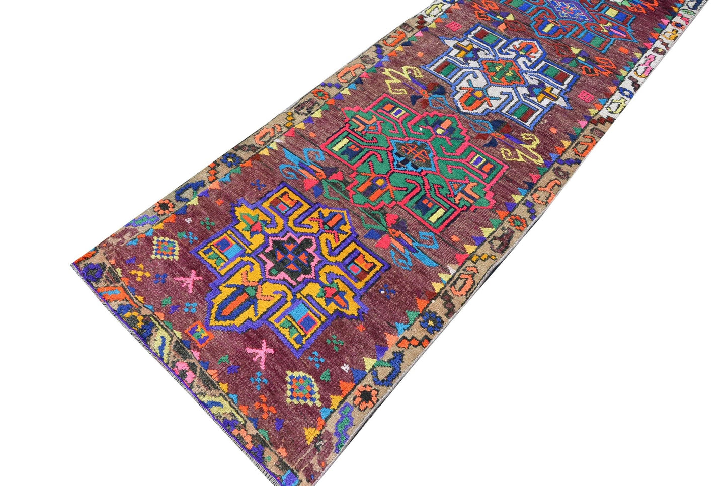 A vintage Kurdish Herki runner featuring vibrant tribal motifs on a deep maroon wool background.