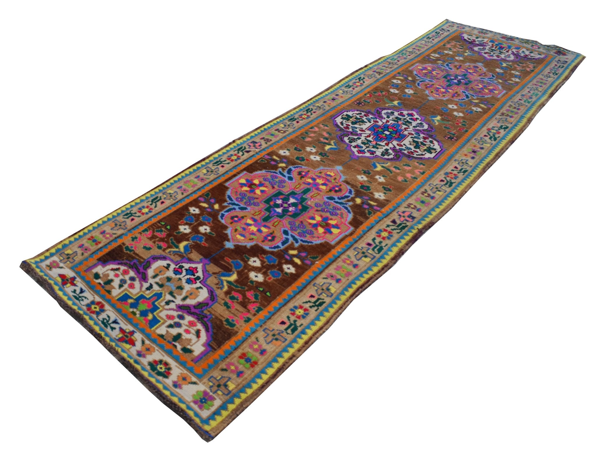 A vintage handmade Kurdish Herki runner featuring colorful tribal motifs on a brown wool background.