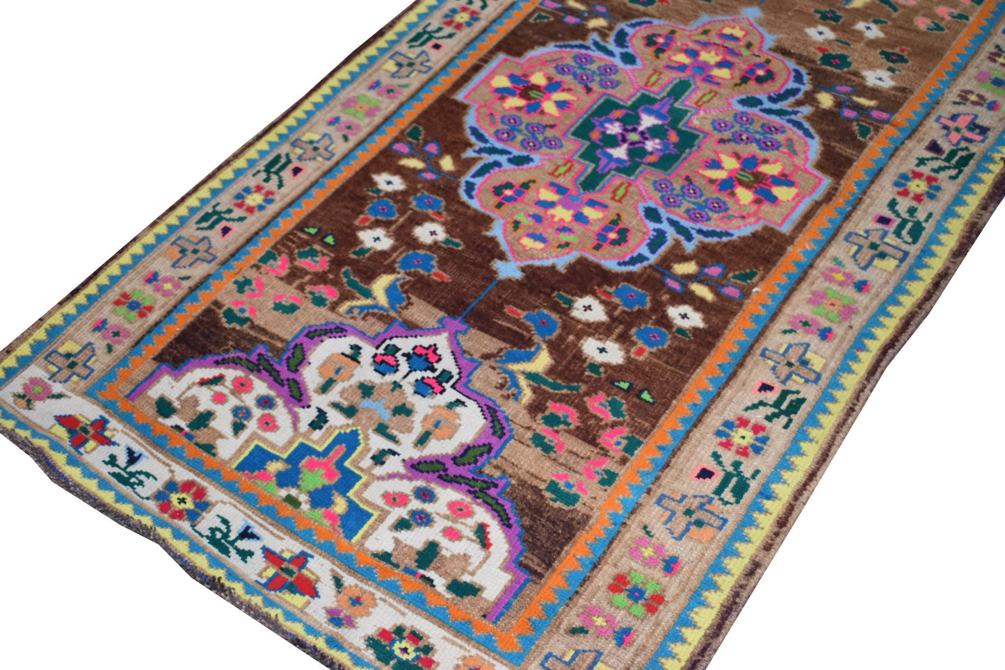 A vintage handmade Kurdish Herki runner featuring a brown field with colorful tribal motifs.