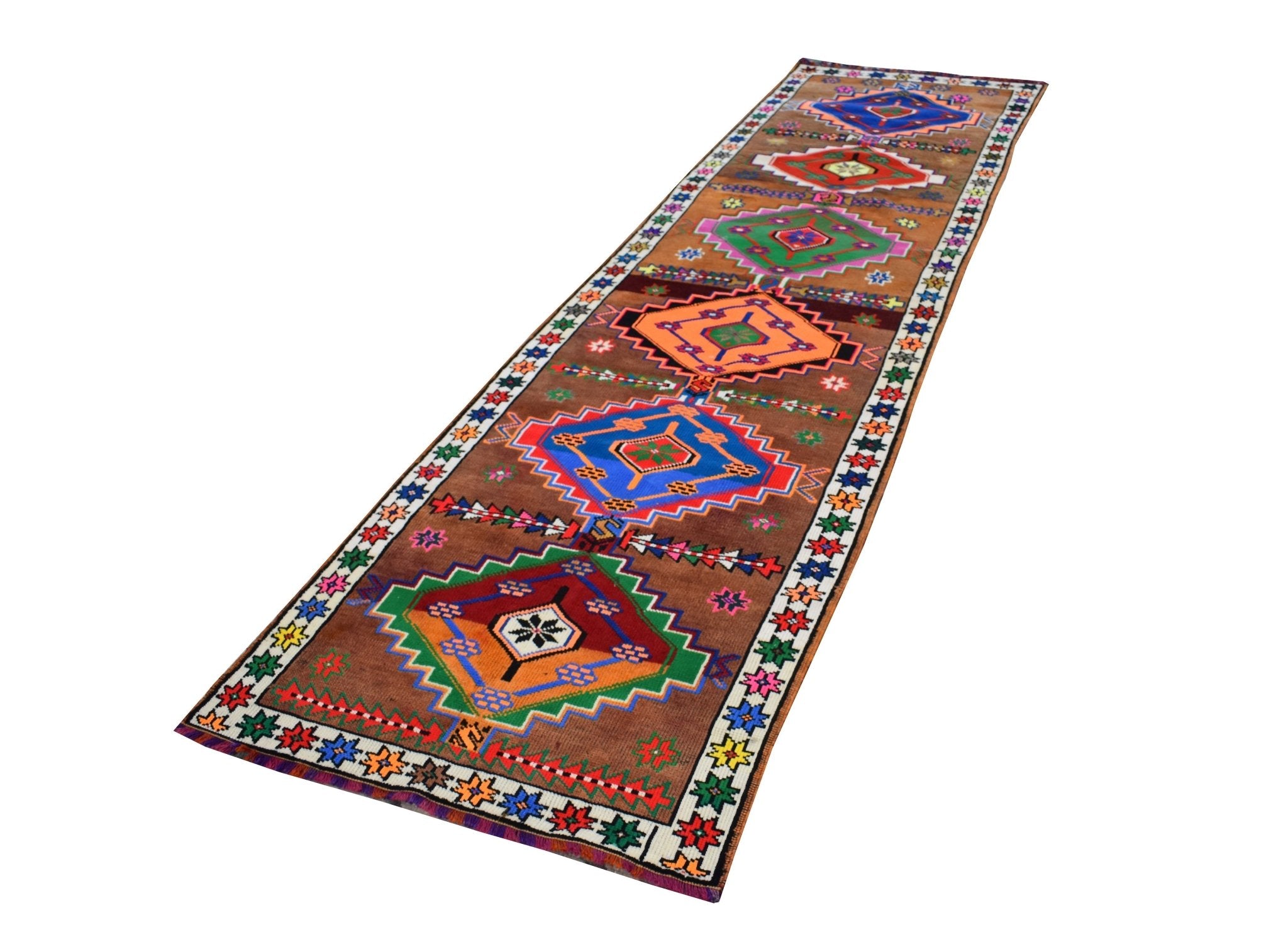 A vintage handmade Kurdish Herki runner featuring colorful tribal geometric motifs on a brown field.