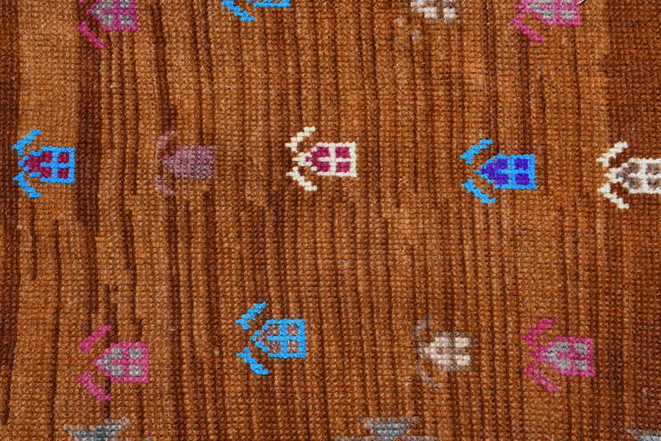 A vintage Kurdish Herki runner featuring tribal motifs in neon colors on a brown wool background.