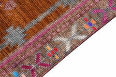 Vintage Kurdish Herki runner with tribal patterns in brown, pink, and gray.