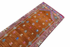A vintage Kurdish Herki runner featuring a brown field with tribal motifs and neon accents.