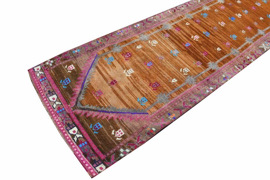 Vintage Kurdish Herki runner with tribal motifs in brown and pink.