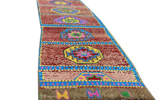 A vintage Kurdish Herki runner featuring geometric medallions in vibrant colors on a red field.