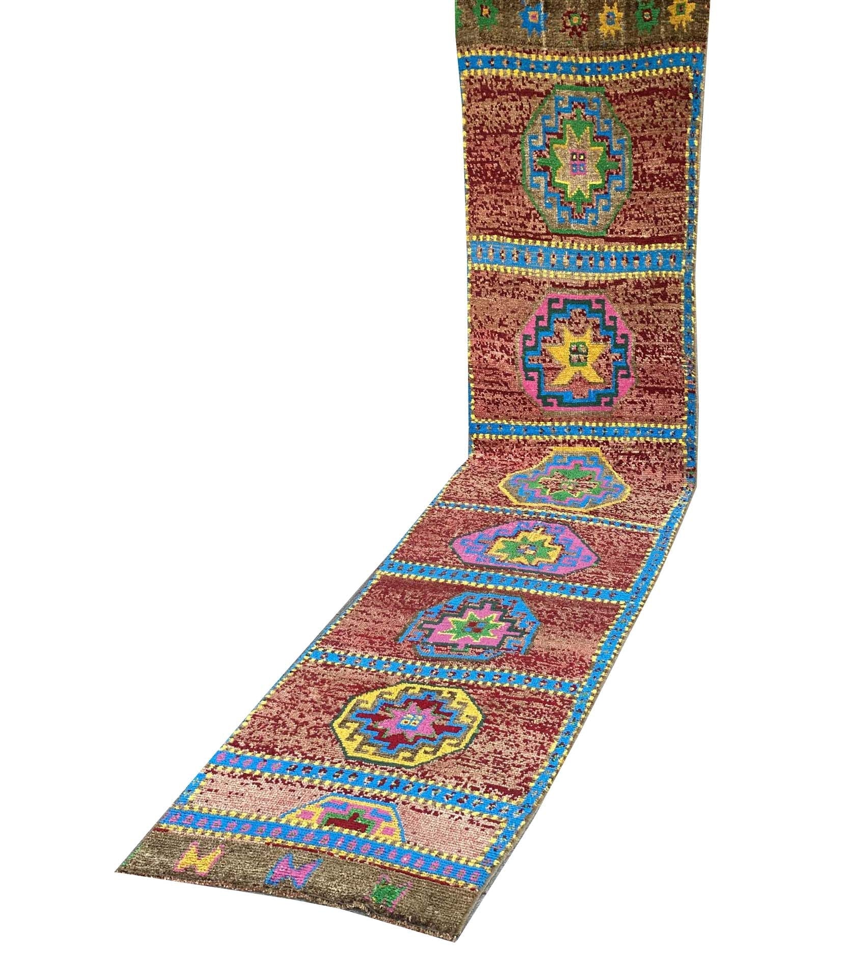 A vintage Kurdish Herki runner featuring geometric medallions in vibrant colors on a red field.