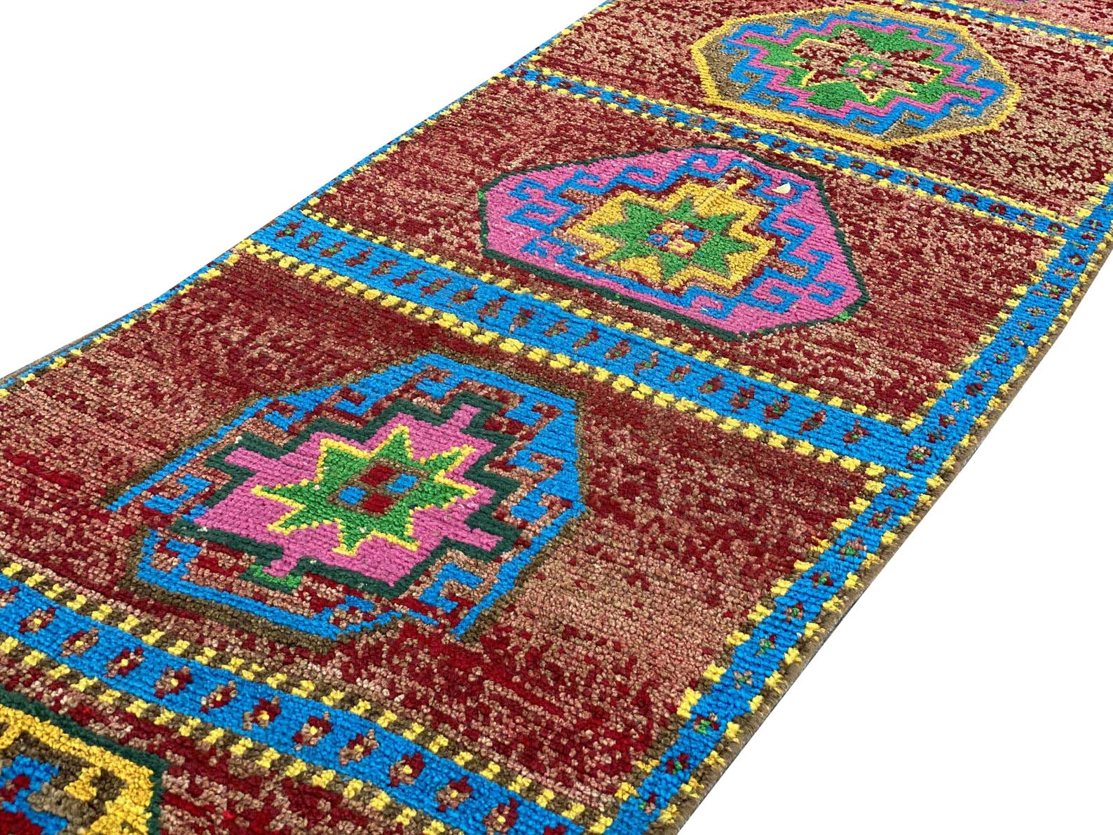 A vintage Kurdish Herki runner featuring geometric medallions in vibrant colors on a red field.