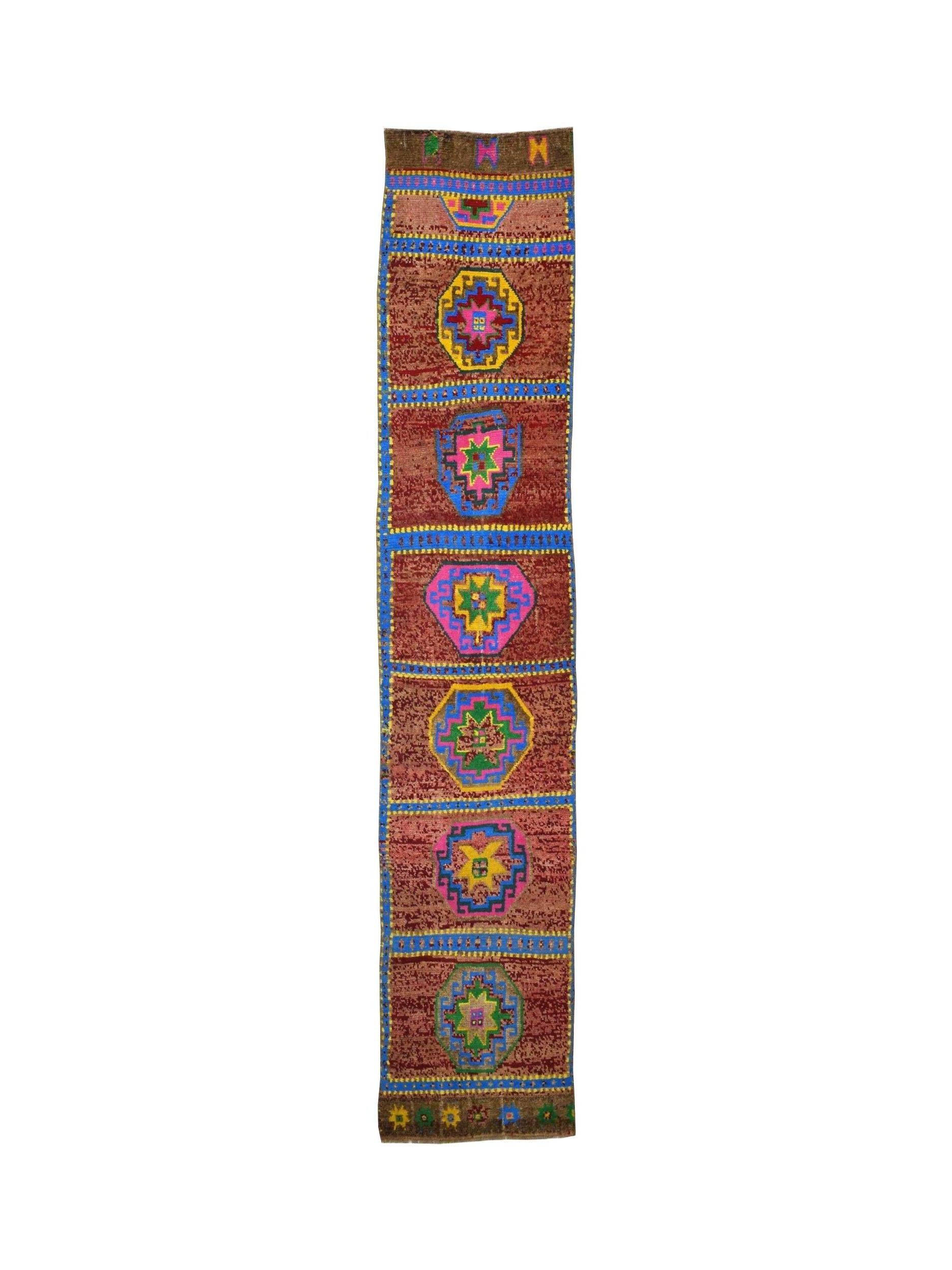 A vintage Kurdish Herki runner featuring geometric medallions on a reddish-brown wool field.