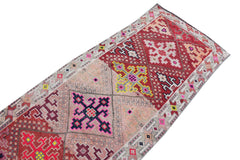 Vintage Kurdish Herki runner with geometric tribal patterns in red, pink, and grey.