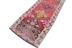 A vintage Kurdish Herki runner featuring tribal geometric motifs in red, pink, and neon accents.