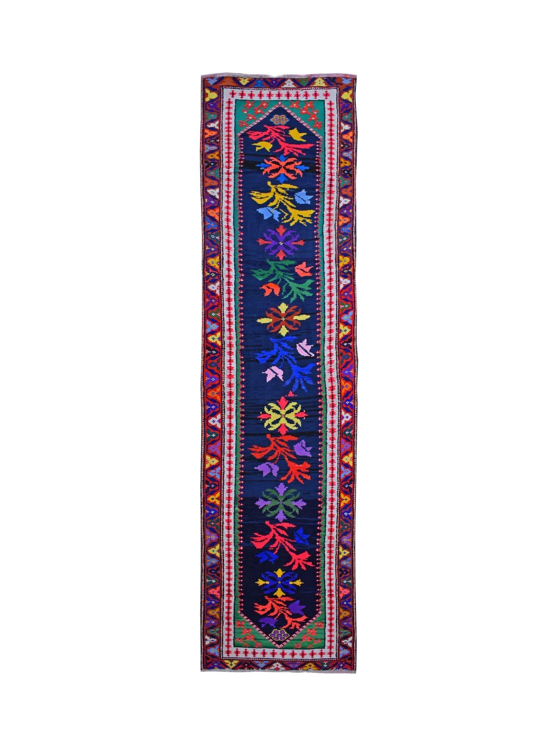 A vintage Kurdish Herki runner featuring vibrant tribal motifs on a deep blue wool background.