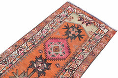 A vintage Kurdish Herki runner featuring tribal motifs in vibrant orange and pink wool.
