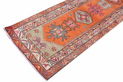A vintage Kurdish Herki runner featuring tribal motifs in vibrant orange and neon colors.