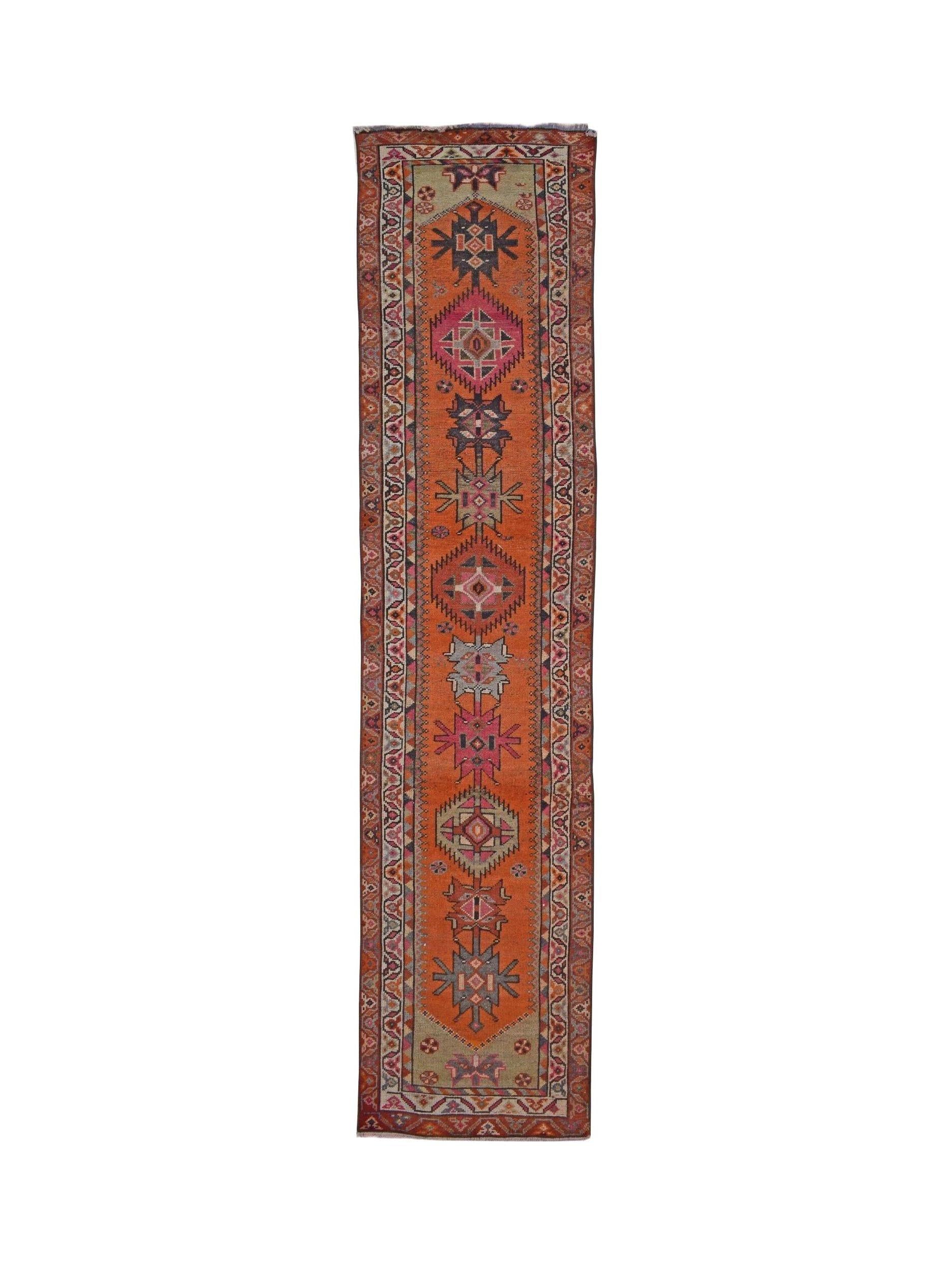 A vintage Kurdish Herki runner featuring tribal geometric motifs in vibrant orange and pink tones.