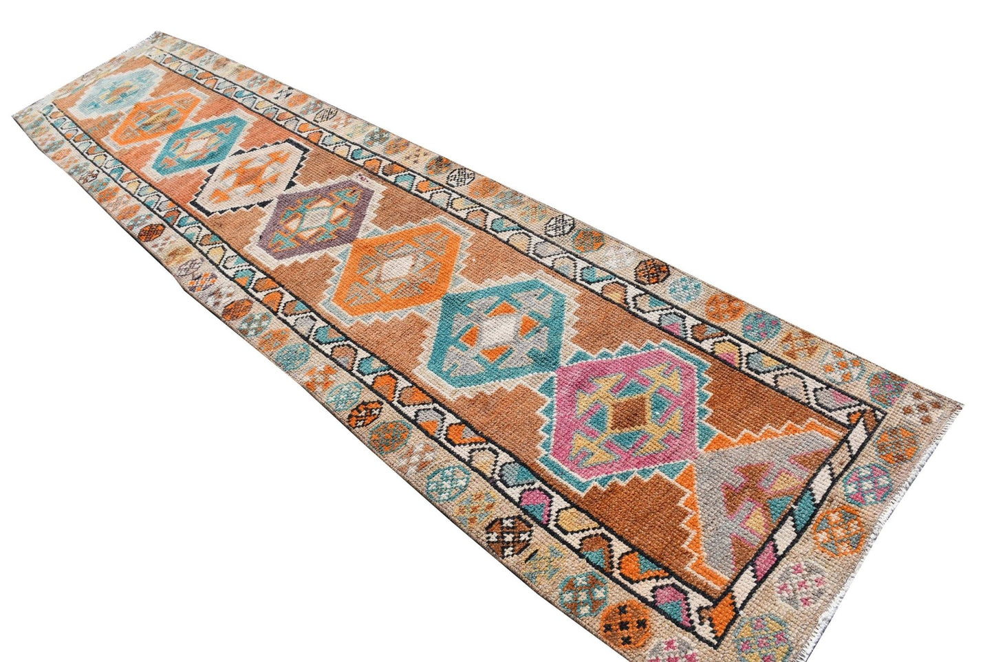 A vintage Kurdish Herki runner featuring geometric tribal motifs in vibrant, multicolored wool.