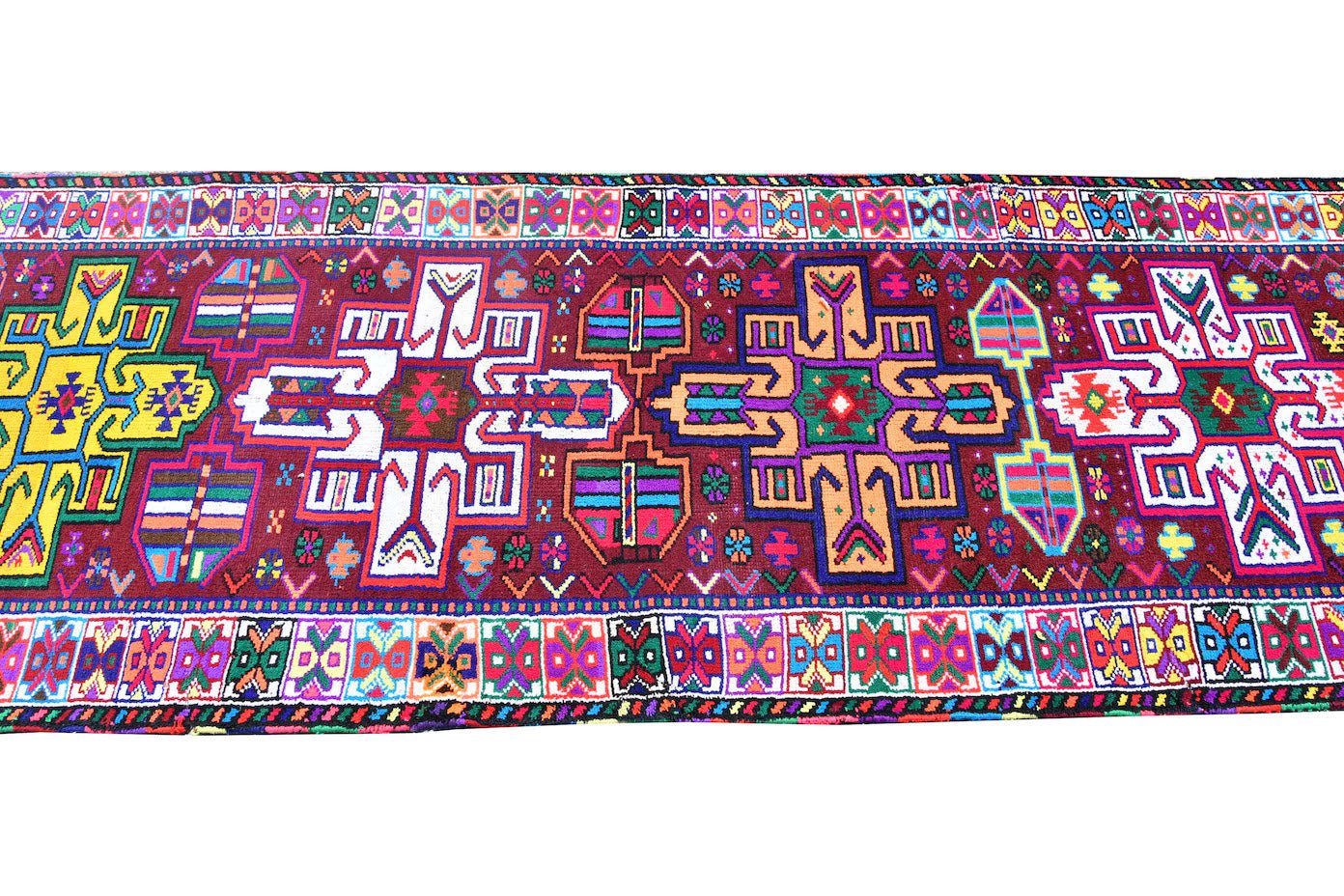 A vintage Kurdish Herki runner featuring vibrant tribal motifs in neon colors on a dark red base.