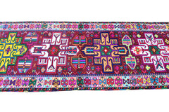 A vintage Kurdish Herki runner featuring vibrant tribal motifs in neon colors on a dark red base.