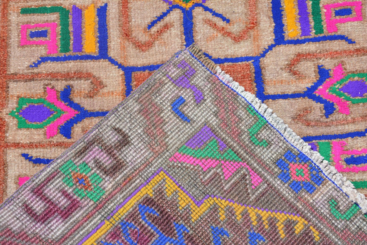 A vintage Kurdish Herki runner featuring tribal motifs in vibrant neon colors on a wool base.