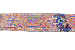 A vintage Kurdish Herki runner featuring vibrant tribal geometric patterns on a wool base.