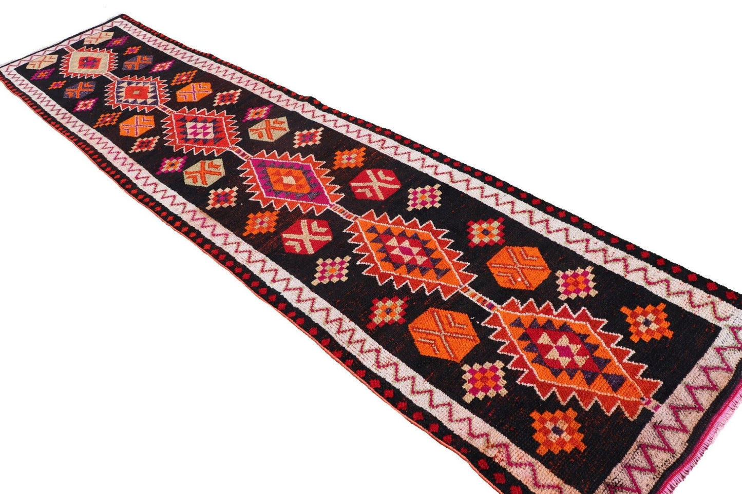 A vintage Kurdish Herki runner featuring tribal geometric patterns in vibrant colors on a black base.