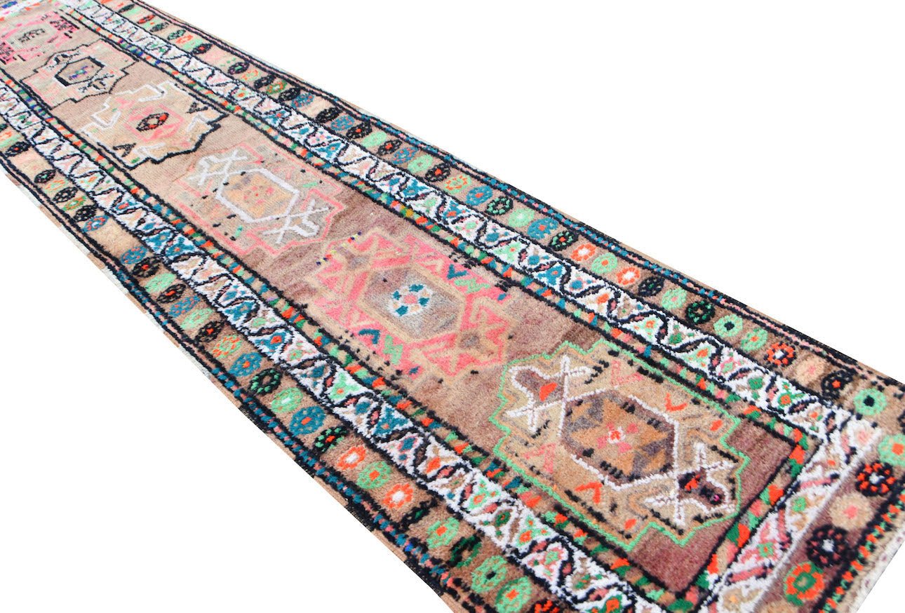 A vintage Kurdish Herki runner featuring tribal motifs in vibrant neon colors on a wool base.