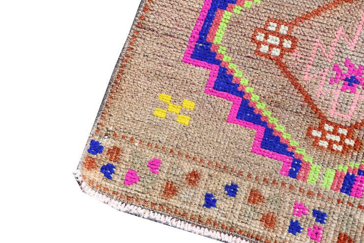 A vintage Kurdish Herki runner featuring tribal motifs in neon colors on a wool base.