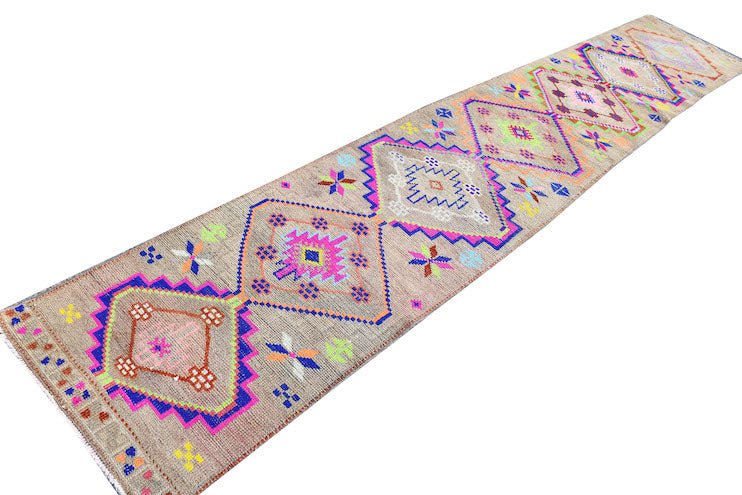 A vintage Kurdish Herki runner featuring tribal diamond motifs in vibrant neon colors on a wool base.
