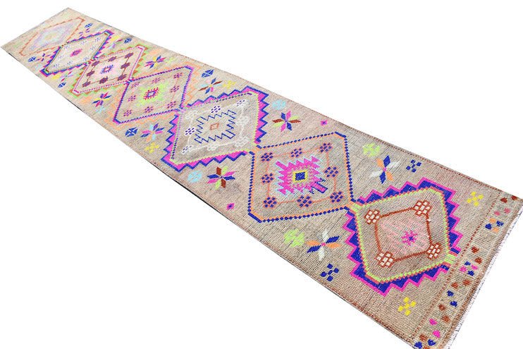 A vintage Kurdish Herki runner featuring tribal diamond motifs in neon colors on a wool base.