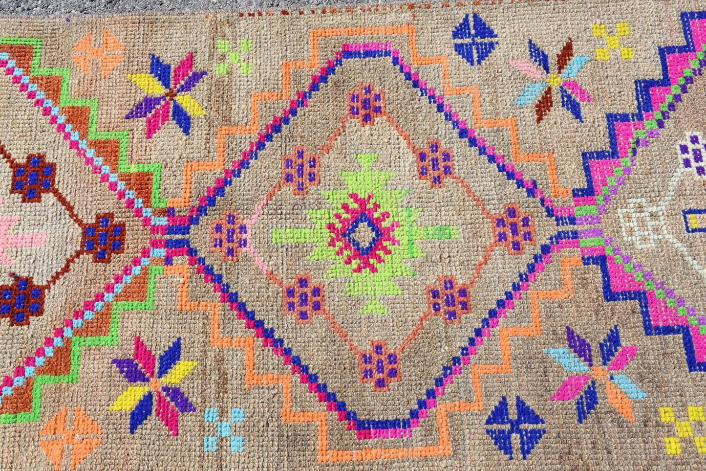 A vintage Kurdish Herki runner featuring a central diamond motif in vibrant neon colors.