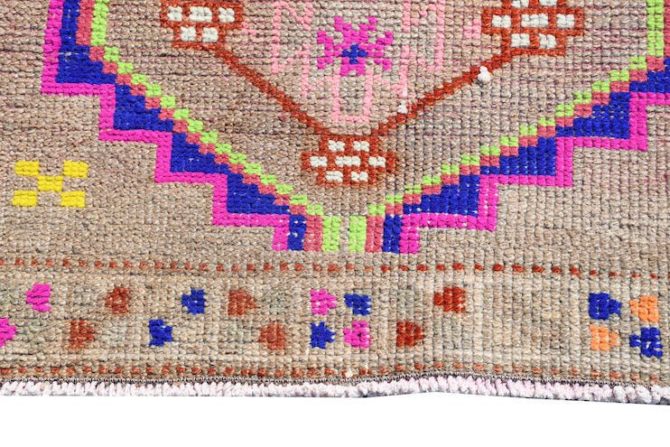 A vintage Kurdish Herki runner featuring tribal motifs in vibrant neon colors on a wool base.