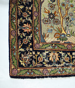A corner detail of a vintage Persian prayer rug featuring intricate floral patterns on a black border.