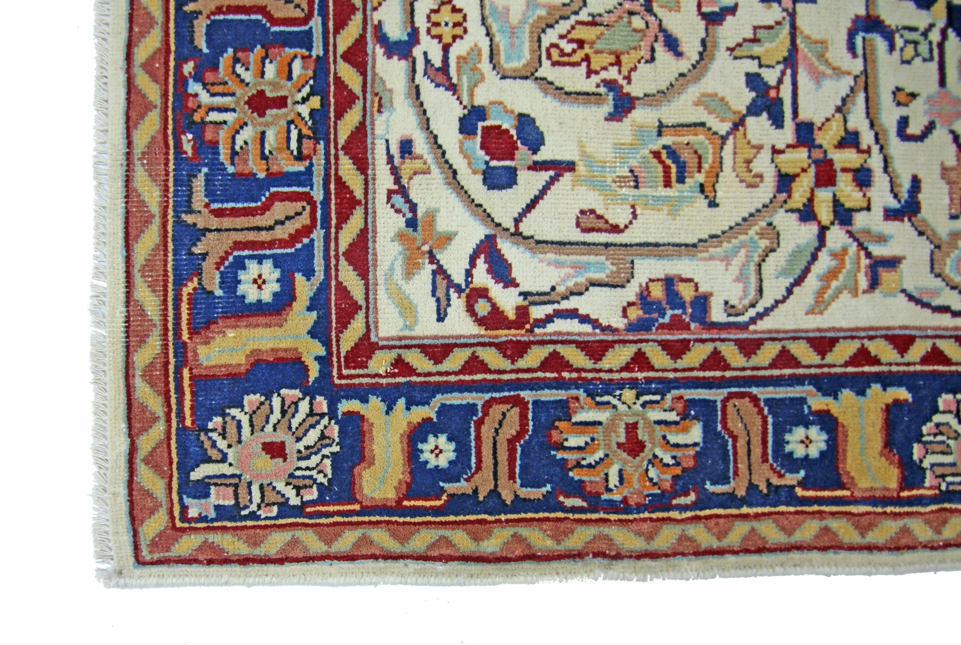 A vintage Pakistani rug featuring a cream center with floral patterns and a blue border.