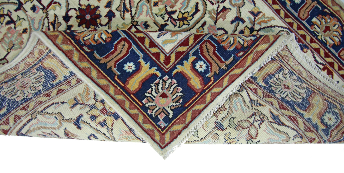 A vintage handmade Pakistani rug with a folded corner revealing its intricate floral pattern.