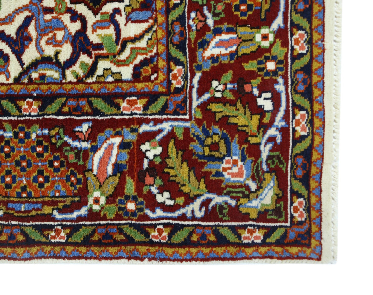 A corner view of a vintage Pakistani wool rug featuring intricate floral patterns in red, blue, and green.