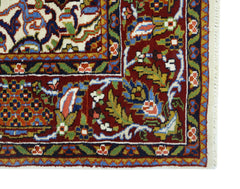 A corner view of a vintage Pakistani wool rug featuring intricate floral patterns in red, blue, and green.