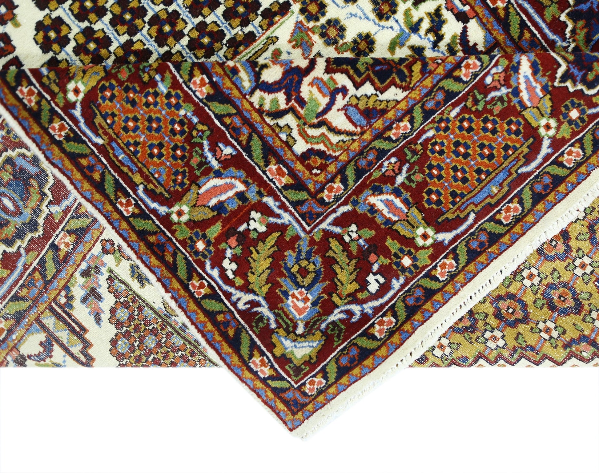 A folded vintage Pakistani wool rug featuring intricate floral patterns in red, blue, and gold.