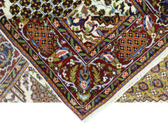 A folded vintage Pakistani wool rug featuring intricate floral patterns in red, blue, and gold.