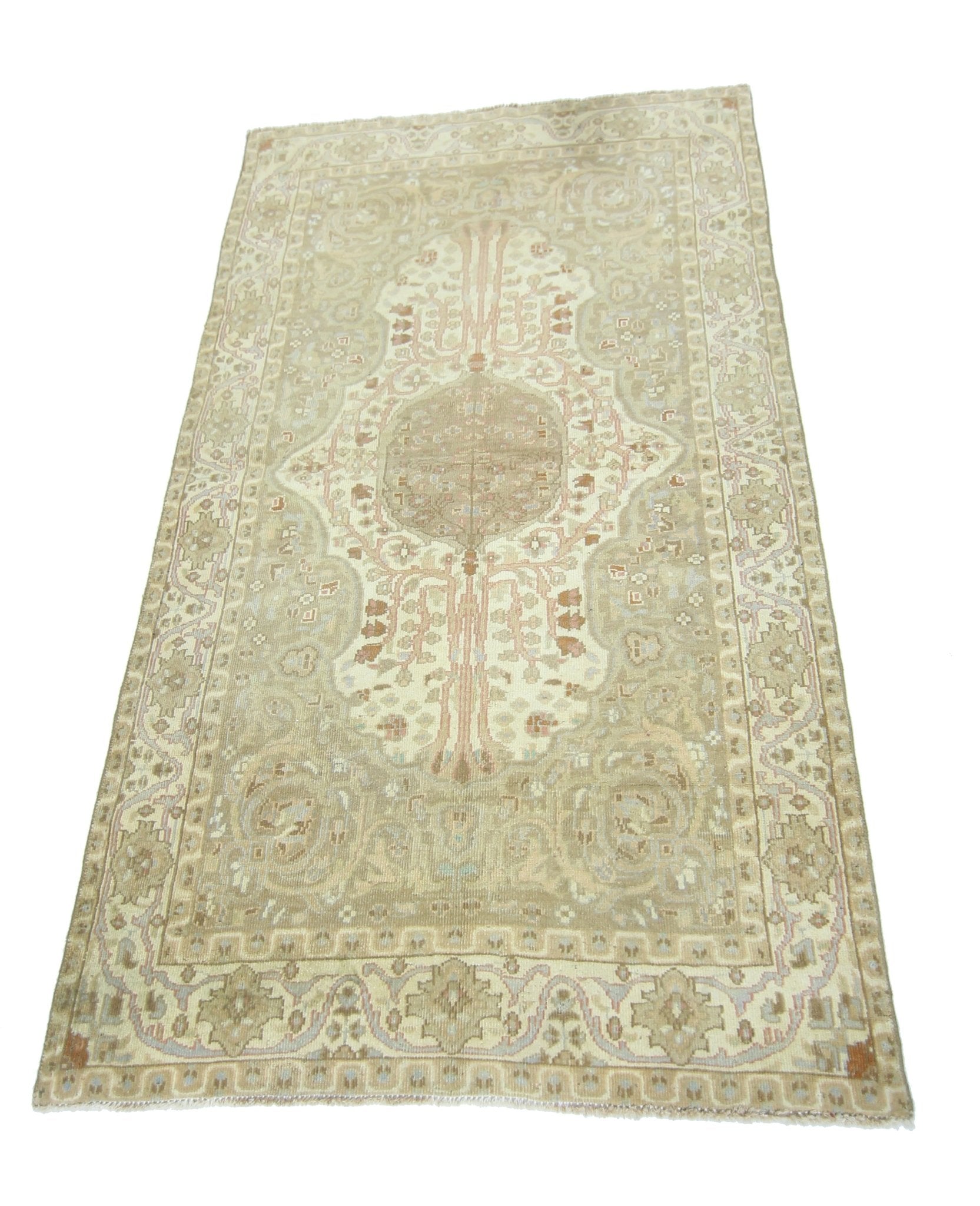 A vintage handmade Pakistani rug featuring a central medallion and floral motifs in neutral tones.