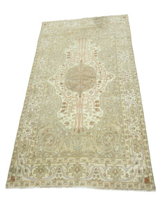A vintage handmade Pakistani rug featuring a central medallion and floral motifs in neutral tones.
